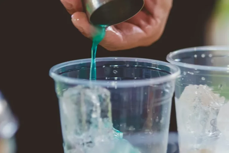Blue drink being poured over ice, like a homemade Ocean Breeze